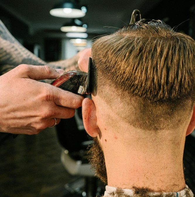 Barber performing a stylish haircut on a man in a modern barbershop.